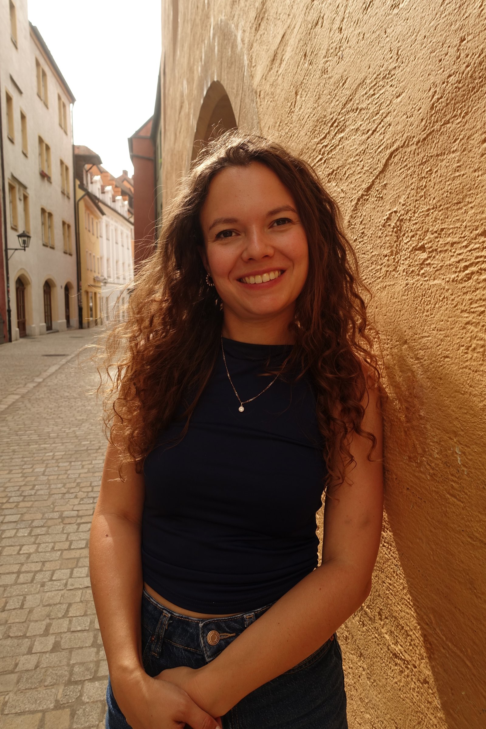 Anna lächelt in einer sonnigen Altstadtgasse